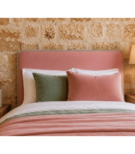 tête de lit rose dans chambre adulte avec mur en pierre et coussins assortis